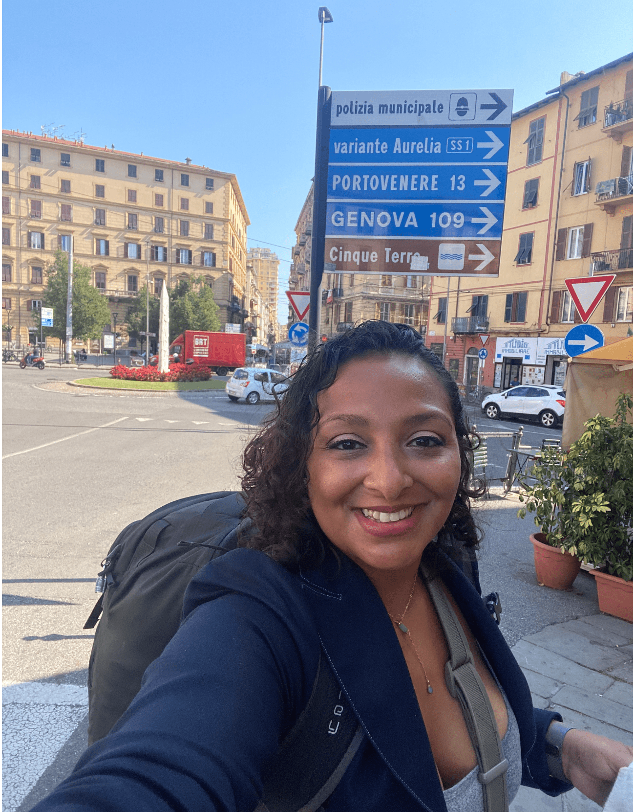 Mujer con una mochila frente a un letrero que muestra los diferentes pueblos de Italia.