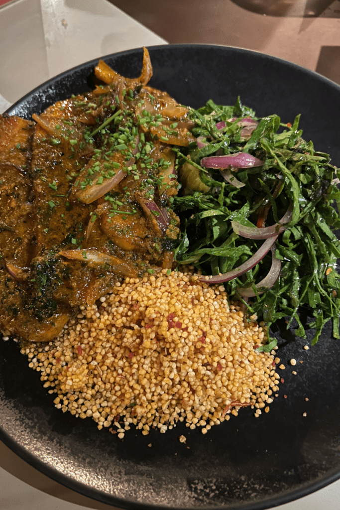 Brazilian dish with seasoned pork loin, farofa, and shredded collard greens served at Yayá restaurant in Rio de Janeiro