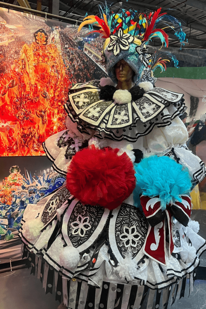 Carnival costume on display at Samba City in Rio de Janeiro with colorful feathers and detailed beadwork alongside Carnival parade photographs