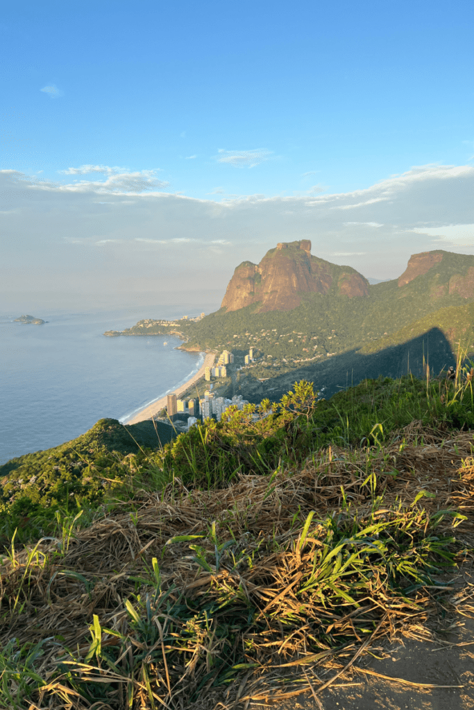 View from the Dois Irmãos hike in Rio de Janeiro looking toward Pedra da Gávea mountain and São Conrado beach at golden hour