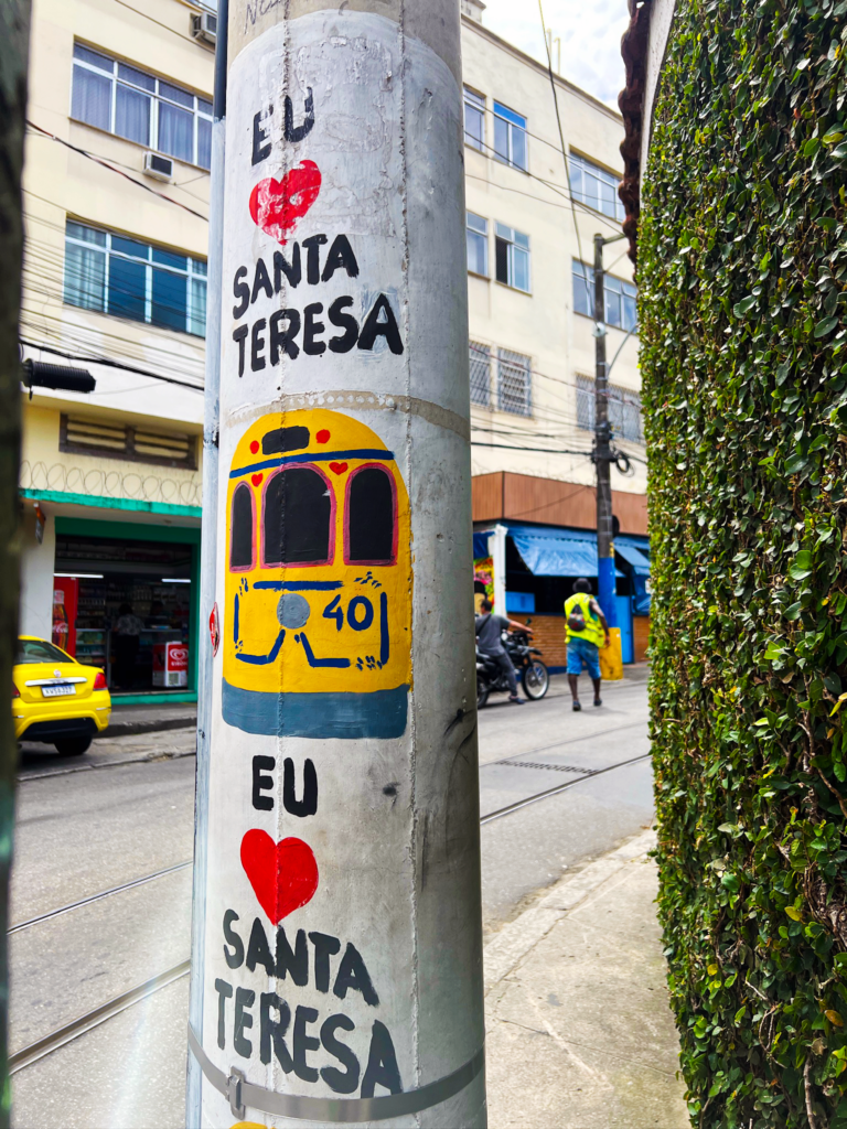 Where to stay in Rio: hand-painted column in the Santa Teresa neighborhood of Rio de Janeiro featuring the iconic yellow Bondinho tram and "Eu ❤️ Santa Teresa" graffiti