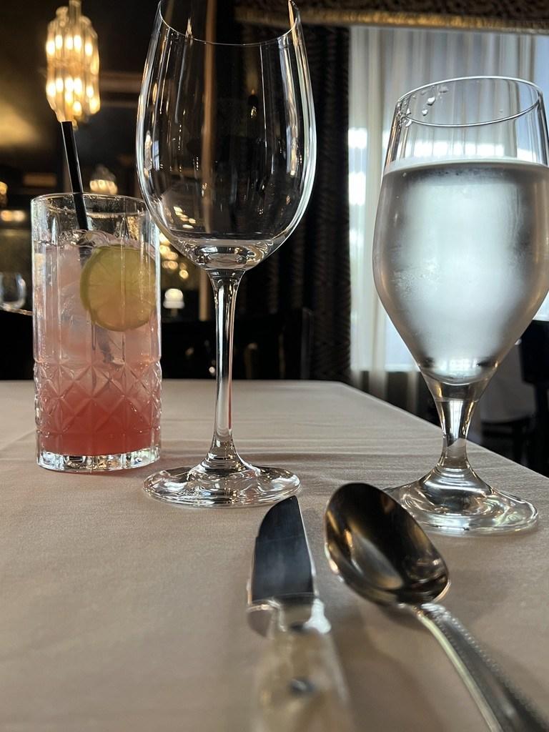 White-tablecloth place setting with a pink cocktail, wine and water glasses at Bridgeman's Chophouse in Chattanooga